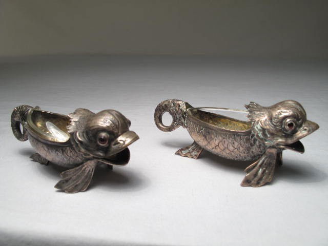 TWO GERMAN 800 SILVER FIGURAL DOLPHIN SALT CELLARS: Two figural salt cellars in the form of a dolphin. German 800 silver. Stamped on lower fin. Each measures 4" long. Both with original clear glass liners. Condition: one glass liner has a chip, see ima