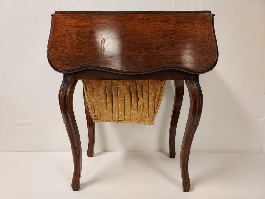 ANTIQUE WALNUT DROP LEAF SEWING TABLE: Antique walnut drop leaf sewing stand or sewing table. Drop front door on one end, with two small drawers and a pull out fabric basket storage area below. Measures a total of 27.75" tall x 23.75" long
