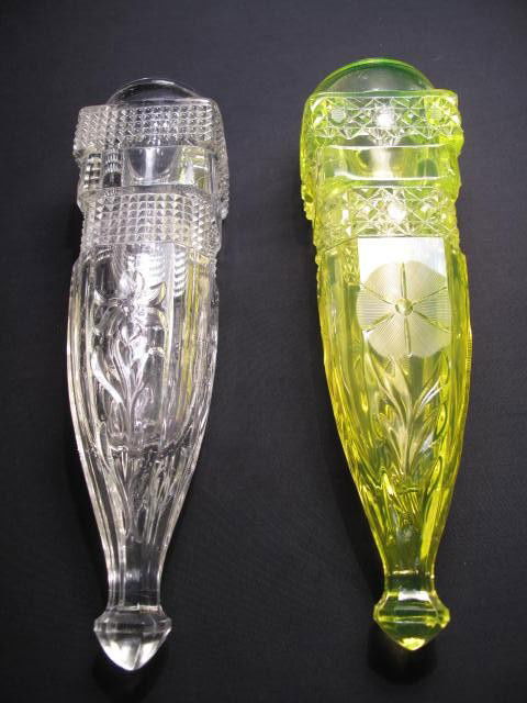 TWO AUTOMOBILE BUD VASES - VASELINE GLASS & CLEAR: Two vintage glass automobile bud vases. The first Vaseline glass with intaglio cut flower design and the second a pressed pattern clear glass with floral design. Each measuring 7 1/2" long. Condition