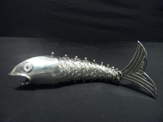STERLING ARTICULATED FISH BOTTLE OPENER: Sterling reticulated fish bottle opener. Mother of pearl inlaid eyes. Mouth designed to be used as bottle opener. Reticulated body with 9 joints. Marked "Sterling" with maker on tail. Condition: good,