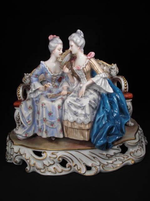 CAPODIMONTE PORCELAIN FIGURAL GROUP: Capodimonte porcelain figural group depicting two Victorian women on a sofa. Marked on base "N" with crown logo above. Painted and gilt. Condition: possible repair to left woman's right pinky finger, 