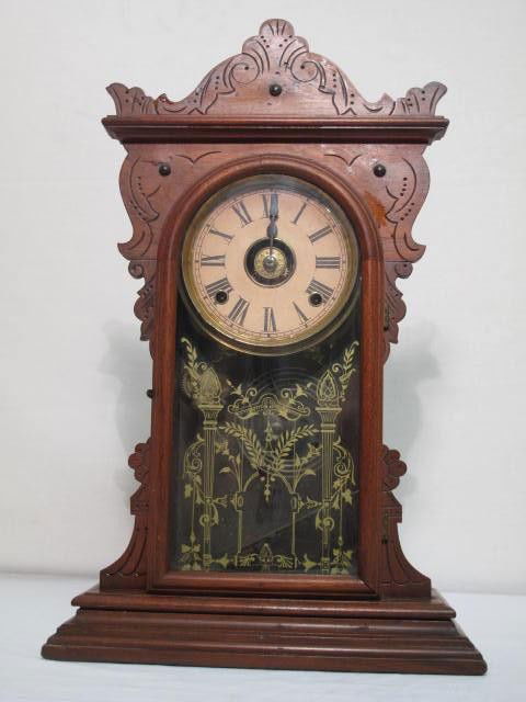 AMERICAN GINGERBREAD CLOCK: American gingerbread style clock. Eight day brass mechanism. Original label (worn, toned, illegible) Measures 21" tall x 13.5" wide. Does not wind. Shipping weight 6.3 lbs.