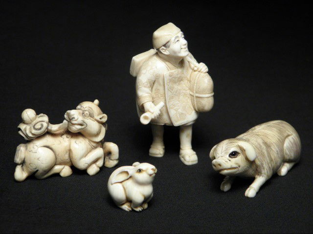 FOUR JAPANESE CARVED IVORY NETSUKES: Four Japanese carved ivory netsukes. Includes a man carrying a pipe, bag, and abacus; a dog; a pig; and a small rabbit. Dog and pig are signed. Condition: small age crack to man, see images. Man measu