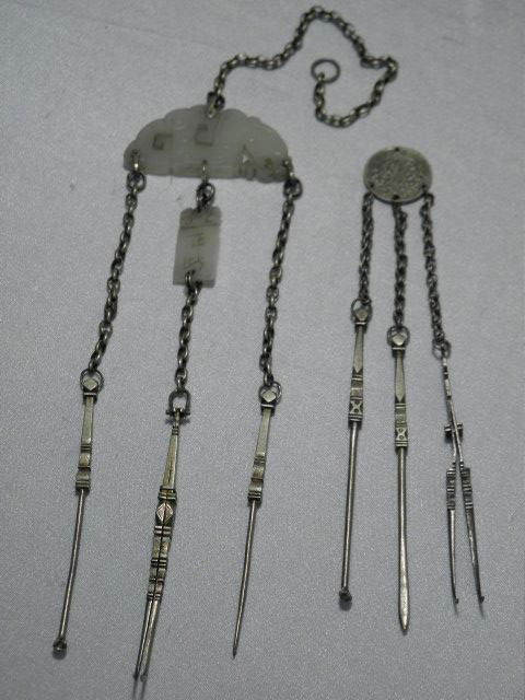 TWO CHINESE SILVER OPIUM TOOL CHATELAINES: Two Chinese silver metal opium tool chatelaines. First chatelaine has a long main chain connected to a carved white jade dragon. Attached to the dragon are three etched opium tools. Center has a carve