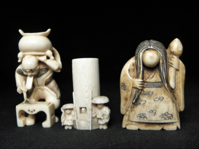 THREE JAPANESE CARVED IVORY KATAKURI "TRICK" NETSU: Three Japanese carved ivory Katakuri or "trick" netsukes. Includes a netsuke depicting two men guarding a building with a woman inside, a man holding a pot and painting a picture, and an old woman. Th