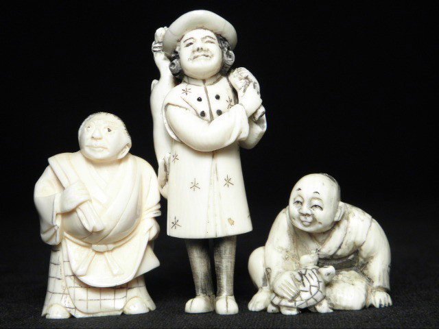 THREE CARVED IVORY NETSUKE: Three Japanese carved ivory Katabori netsuke. Includes a man sitting with turtle, a portly man standing, and a woman carrying a dead rabbit. All are signed, the two men signed on base, woman signed on