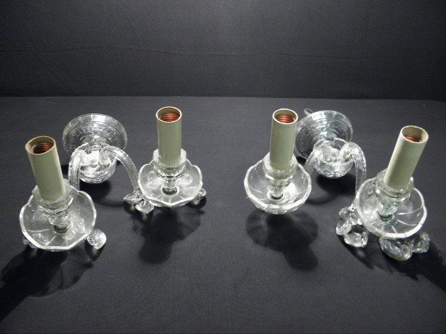 CUT CRYSTAL DOUBLE ARM WALL SCONCES WITH PRISMS: Pair of cut crystal double arm wall sconces with prisms. Each sconce holds two bulbs and has various prisms hanging below. Condition: minor chips to inside edge where crystal bowls attach to base of l