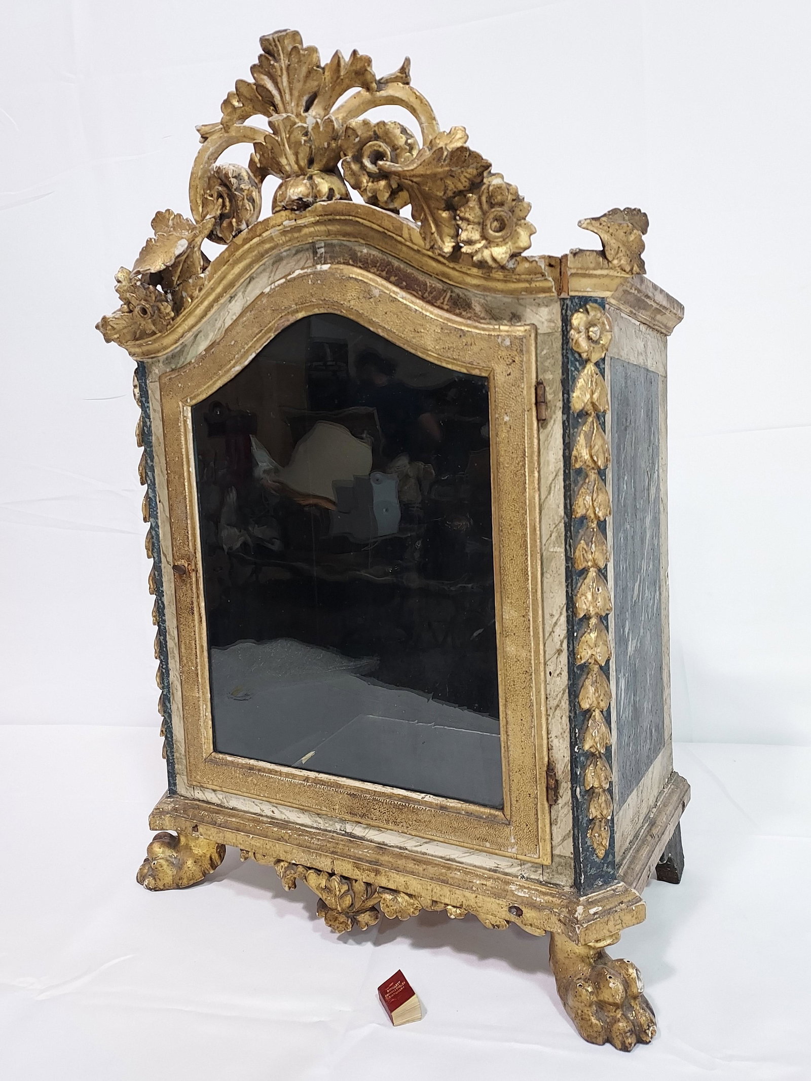 ANTIQUE CARVED WOOD ITALIAN RELIQUARY CABINET: A 19th century Italian wood and glass one door reliquary cabinet. Dome top with wood carved floral & foliage gallery, applied carved bellflower trim on each side of door, and gilded paw feet. Probably