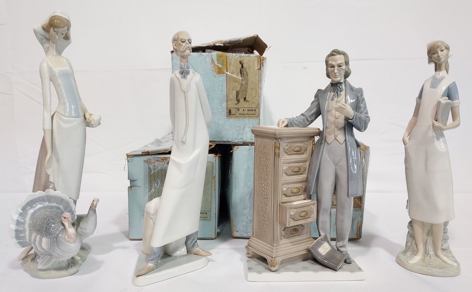 FOUR LLADRO SPANISH PORCELAIN FIGURINES: Lot of four Lladro Spanish porcelain figurines. Includes Lawyer 5213, Medic / Doctor 4602, Nurse 4603, and Woman with Turkeys 1038. Tallest is the Woman with turkeys at 15.25". All include their box e