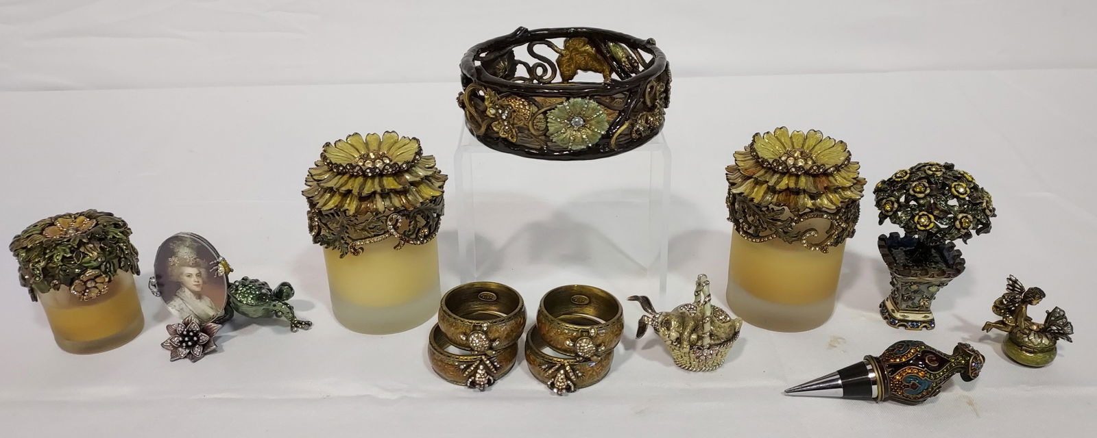 JAY STRONGWATER ENAMELED ACCESSORY LOT 13PCS: Collection of 13 accessories by Jay Strongwater. Includes (2) matching large floral candle or jar toppers, one smaller votive topper, a tree form box, a champagne coaster, frog form picture frame, an
