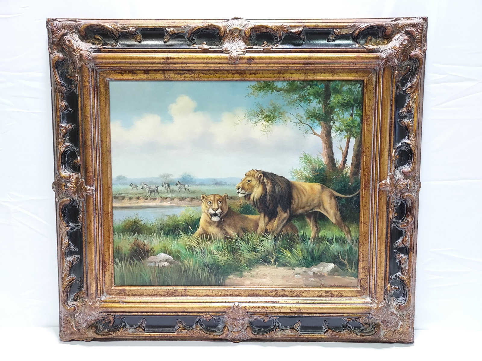 DECORATIVE OIL ON CANVAS PAINTING: LION & LIONESS: Decorative oil on canvas painting depicting a lion and lioness with zebra in the background. Signed "R. Anderson" lower right. Measures (frame) 30.5" tall x 34.5" wide x 2" thick, and (sight) 19" tall