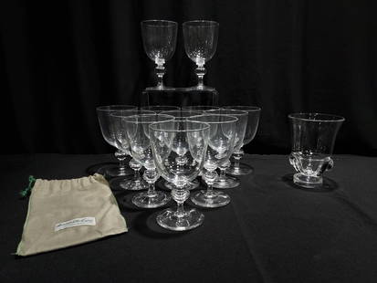 STEUBEN GLASS: TWELVE 7925 STEMS & SCROLL VASE: Steuben glass lot composed of (12) 6.5" pattern 7925 clear glass water goblets, and a 6" tall footed scroll vase. Includes Steuben box and dust bags for stems. Condition: small flake to foot on one of