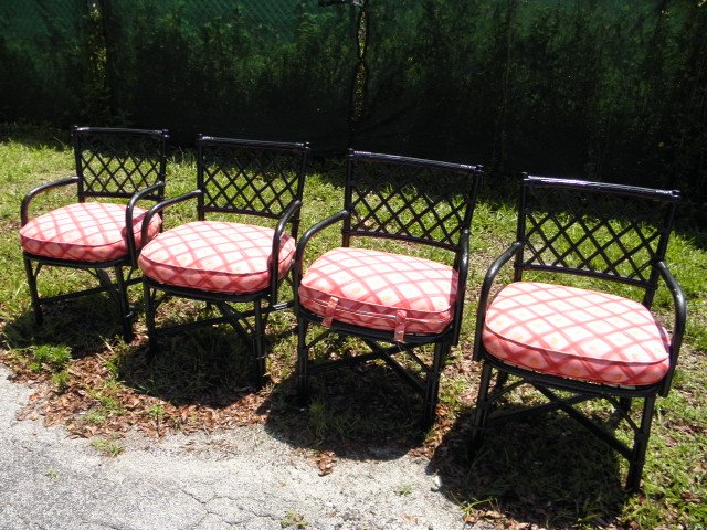 FOUR BLACK PAINTED RATTAN ARMCHAIRS: Four black rattan armchairs with pink, red and orange patterned cushions. Condition: minor chipping and flaking to paint in some areas, see images. Each chair measures 34" tall to the back, 15.5" tall