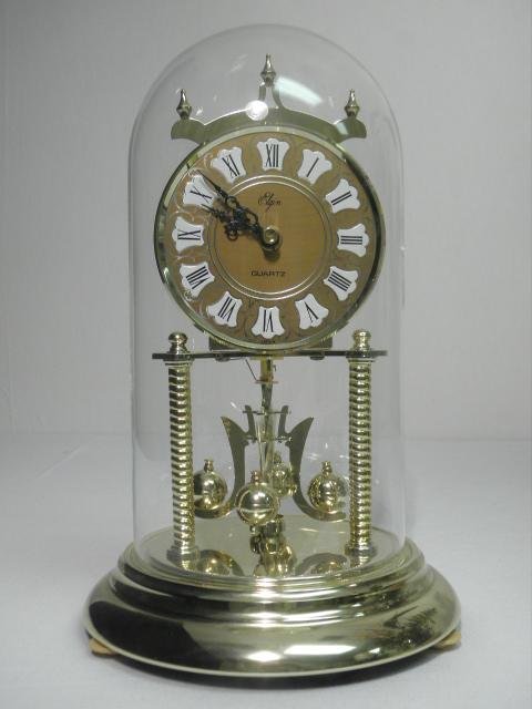 ELGIN BRASS ANNIVERSARY CLOCK: Elgin brass anniversary clock with a glass dome cover. Quartz movement. Condition: missing battery cover (does not affect performance), see images. Measures 12" tall to top of dome. Shipping weight 4 