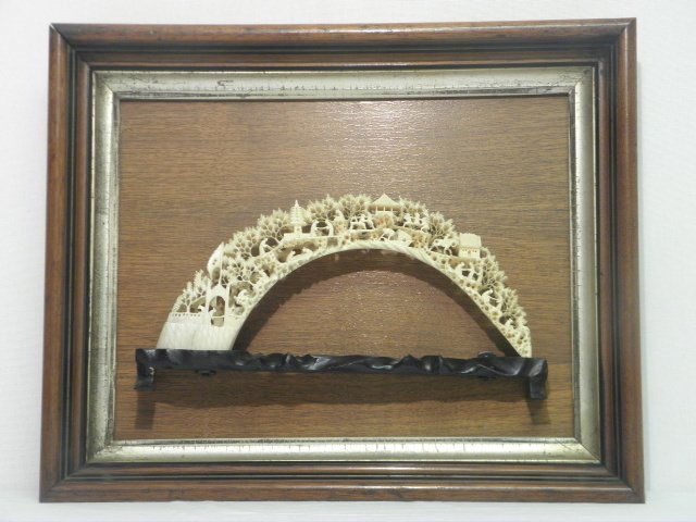 CHINESE CARVED IVORY BRIDGE: Chinese carved ivory bridge depicting an intricate village scene. Mounted to a carved wood base, which is mounted to a wooden display frame. Condition: small repair to horse on mid right side, see ima