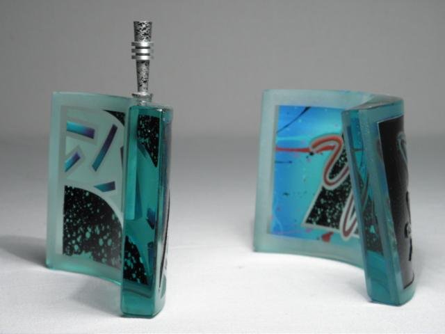 TWO IRVING GLASS DESIGN ART GLASS COLOGNE BOTTLES: Two art glass cologne bottles by Irving Glass Design. Both feature curved glass, drilled and reverse painted with colorful geometric patterns. Both are signed on base "Irving Glass Design 1989". Condi