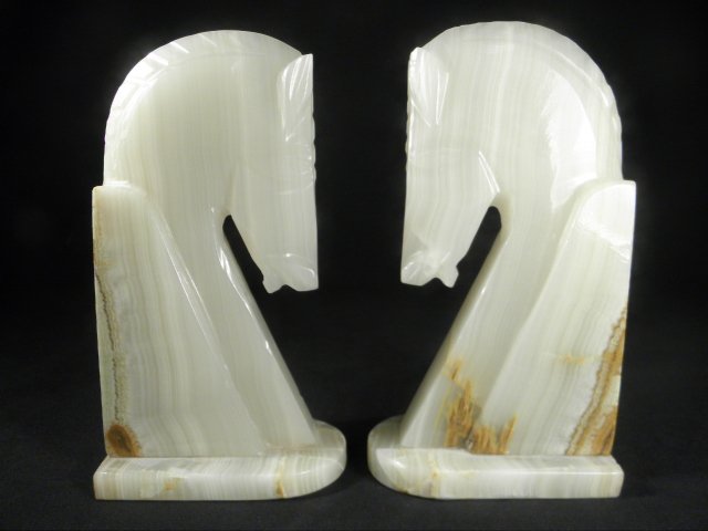 PAIR CARVED ALABASTER HORSE HEAD BOOKENDS: Pair of carved Alabaster horse head form book ends. Two pieces are bolted together from the base. Condition: small loss to left ear of one horse, see images. Each bookend measures 8.4" tall x 4.5" wid