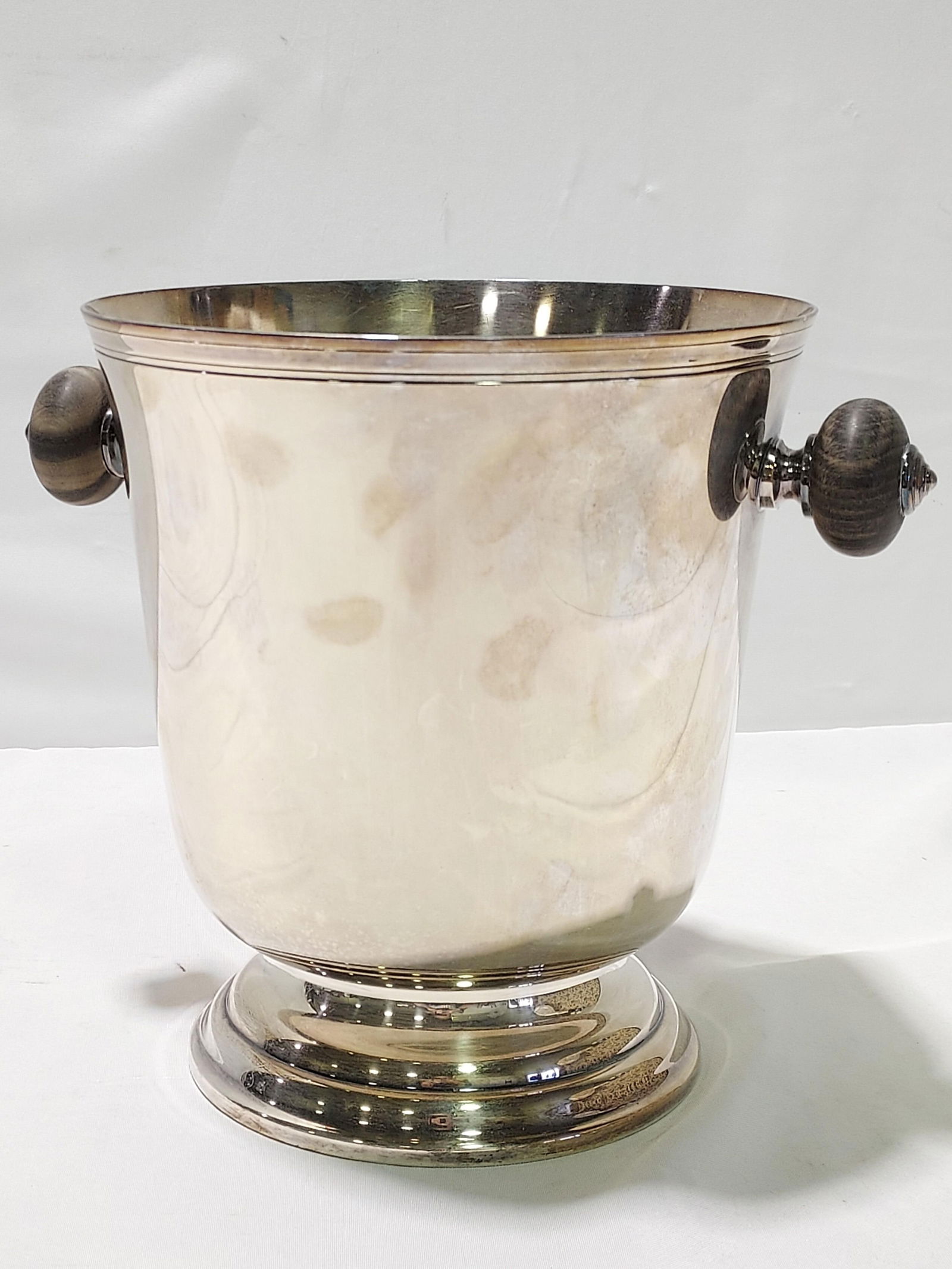 CHRISTOFLE SILVER-PLATED & EBONY CHAMPAGNE BUCKET: Christofle silver-plated and ebony wood champagne bucket or wine cooler measuring 9.1" tall x 8.25" diameter, or a total width of 11.25" from handle to handle. Marked appropriately on base. Condition:
