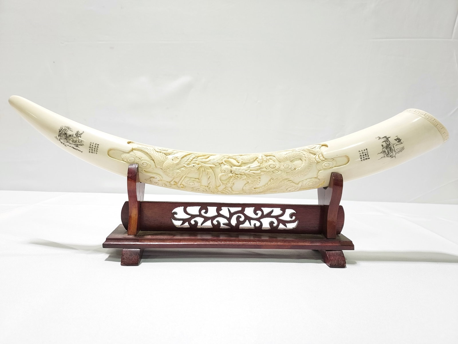 CHINESE CARVED BONE & SCRIMSHAW TUSK: Chinese carved bone tusk with detailed scrimshaw scenes and inscriptions at either end. Tusk measures a total of 22.75" long. Stand measures 12" long. Condition: good, no signs of damages, see images.