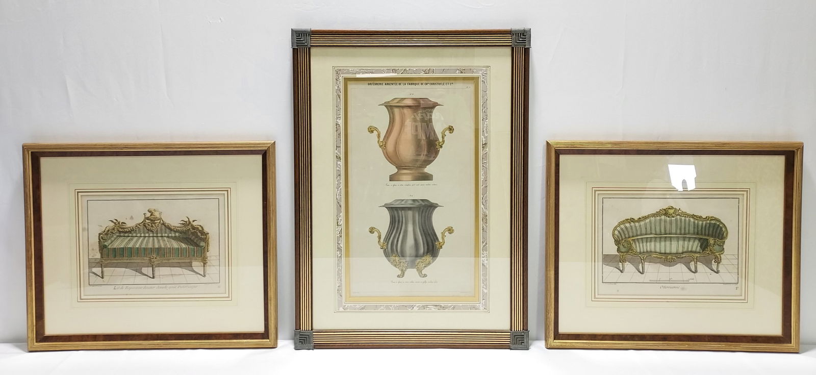 THREE FRAMED HAND COLORED LITHOGRAPHS: Three framed hand colored lithographs. Two depicting antique settees - one Neoclassical, one Rococo, in a gold toned and burl wood frame. The third lithograph is of two Christofle urns framed in a woo