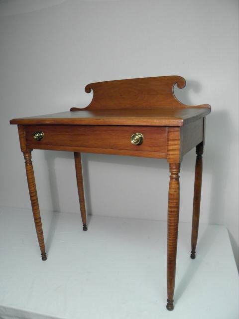 SHERATON STYLE CURLY MAPLE DRESSING TABLE: A 19th century Sheraton style curly maple dressing table with a scrolled back splash and single front drawer. Curly/flame maple patterns show most prominently on legs and sides of table. Condition: re