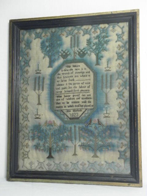 EARLY AMERICAN NEEDLEPOINT SAMPLER: ANN KEYLOCK, 18: An early American cross stitch needlepoint sampler. Features a verse surrounded with floral decorations, signed and dated underneath "Ann Keylock, 1823". Condition: needlepoint colors have run with ag