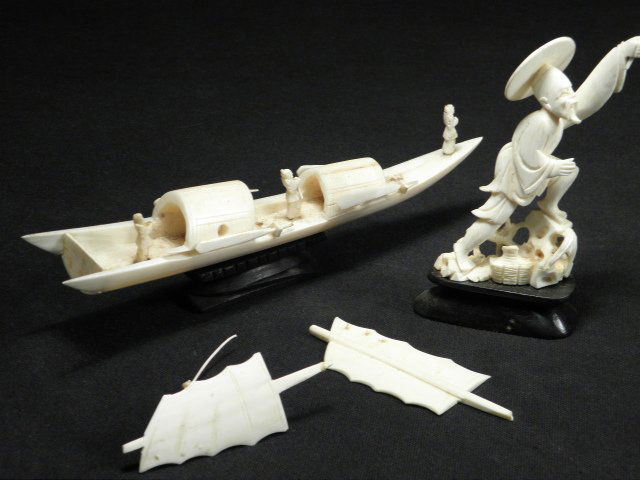 CHINESE CARVED IVORY FISHERMAN & SAMPAN: Lot including a Chinese carved ivory fisherman with dog figure, and a Sampan boat (or junk/sailboat). Both are mounted to carved wood bases. Condition: two sails are broken off of the sampan, but are