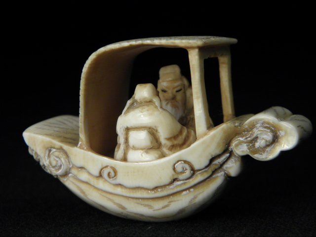 CHINESE CARVED IVORY DRAGON BOAT NETSUKE: Chinese carved ivory netsuke depicting two figures in a dragon boat. Artist signed on base,and includes box. Condition: some remains of white highlights in carved details, very minor discoloration wit