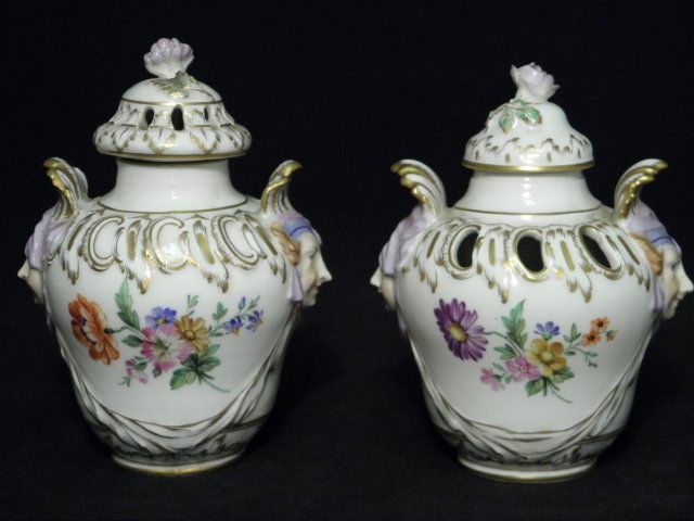 TWO KPM BERLIN PORCELAIN COVERED POTPOURRI JARS: Two 19th century Berlin (K.P.M.) porcelain covered potpourri jars. One with pierced lid. Both are hand painted with florals and gilt highlights, figural handles on each side, and a rose finial. Bases
