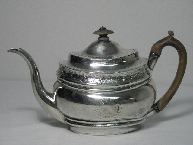 THOMAS WALLIS II STERLING SILVER TEAPOT - 13.7 TRO: Thomas Wallis II sterling silver teapot. Circa 1800, with a wooden handle, finial, and an engraved floral pattern. Stamped on base with various marks, including the British sterling silver standard ma