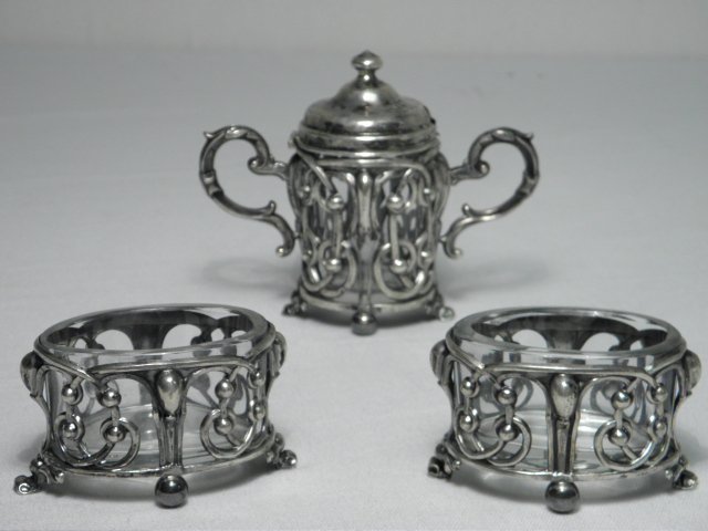CONTINENTAL SILVER THREE PIECE CONDIMENT SET: A continental silver and glass three piece condiment set. Includes (2) 3.15" wide open salt cellars with glass inserts, and (1) 4.25" tall lidded mustard cellar with glass insert. Mustard cellar is st