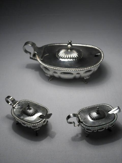 THREE ITALIAN SILVER SALT CELLARS: ONE LARGE, TWO: Lot of three Italian silver salt cellars. Includes two small 2" tall x 3" long salt cellars with spoons, and a large 3" tall x 6.4" long salt cellar. All three cellars include a fitted clear plastic i