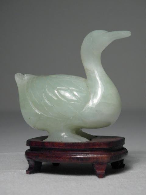 CHINESE CARVED NEPHRITE JADE DUCK: A Chinese carved green Nephrite jade duck. Includes small wooden fitted stand. Condition: small loss to back of duck's left foot, see images. Measures (jade only) 2.5" tall x 3" long. Shipping weight 
