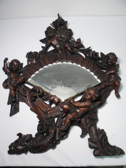 ROCOCO STYLE CARVED WALNUT CHERUB MIRROR: Rococo style carved walnut mirror. Hand fan shaped reverse etched glass mirror with a beveled edge. Condition: minor scattered losses and repairs, two major repairs to wood on left side, see images fo