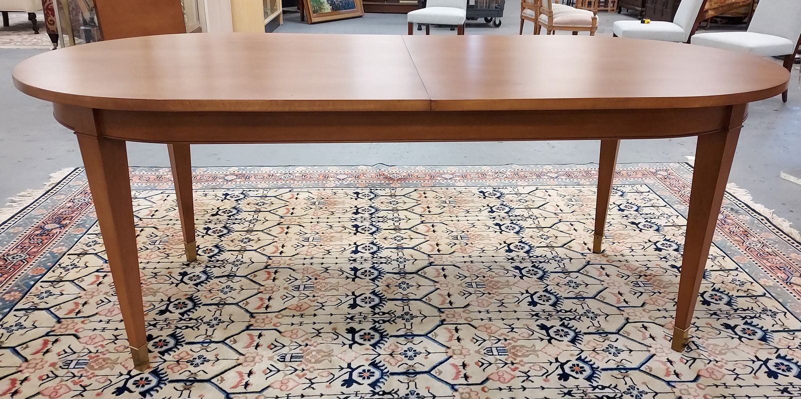 OVAL BAKER THOMAS PHEASANT YVES EXPANDABLE DINING TABLE: Oval Baker Furniture Co. Dining table. Yves table designed by Thomas Pheasant. Unsigned. Extra leaf -24" w. Brass feet, simple skirt. Table without leaf measures 78" long x 38" wide and 30" tall. Good