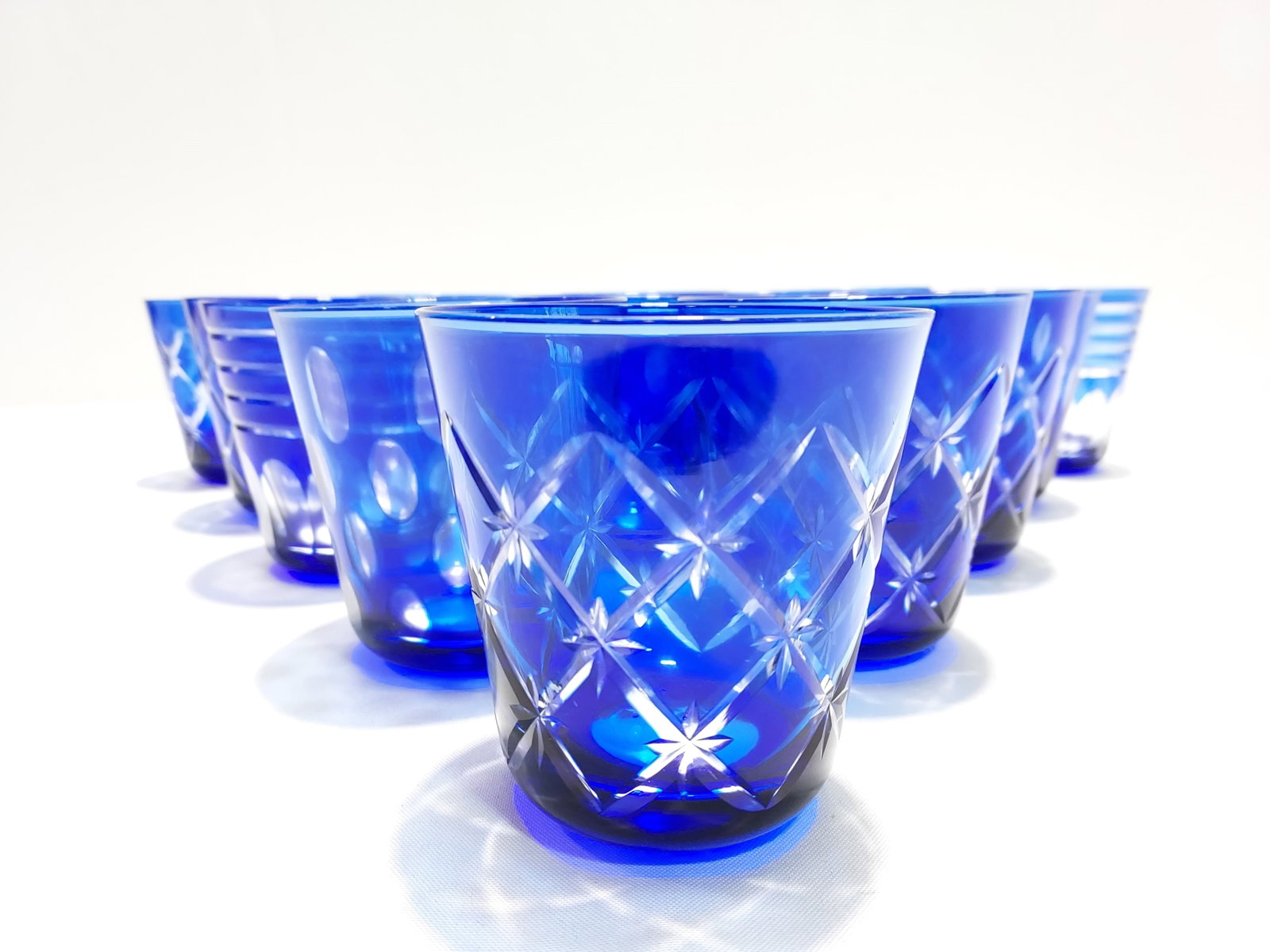 FIFTEEN CZECH COBALT CUT TO CLEAR TUMBLERS: Set of fifteen Czech cobalt cut to clear tumblers, each measuring about 4.1" tall. Unmarked / unsigned. Includes a variety of three different patterns. Condition: one has a chip to rim, see images. We