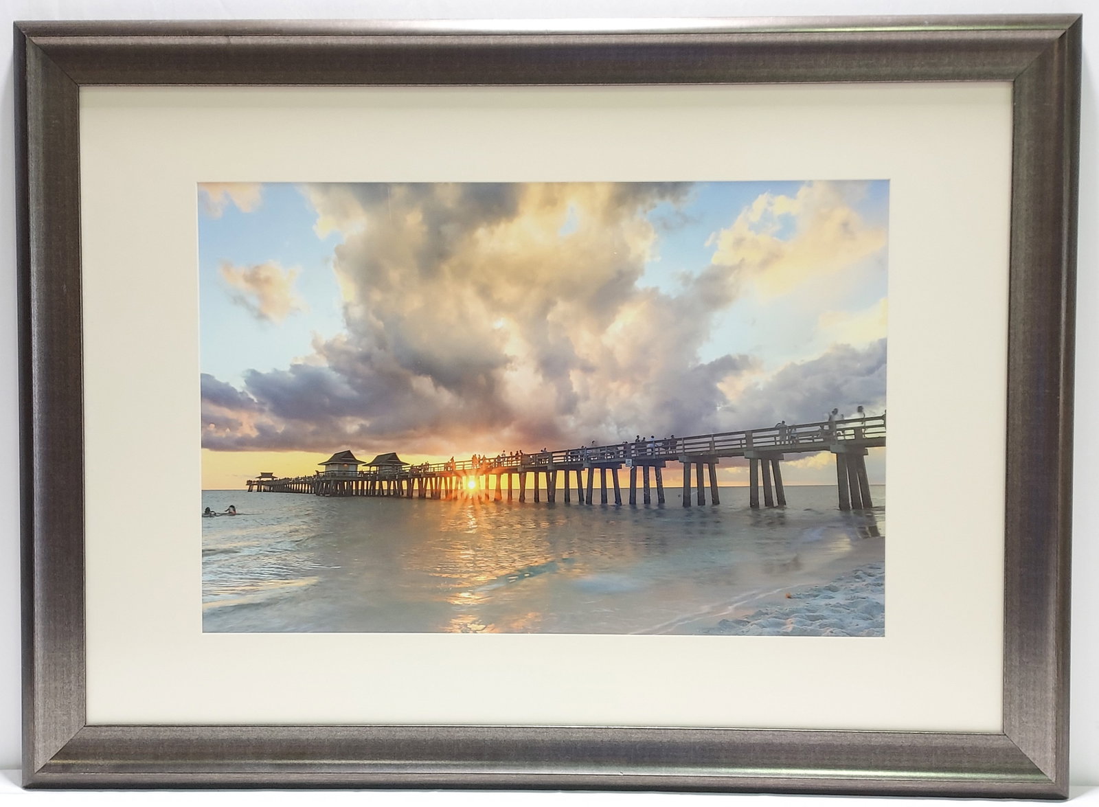 FRAMED PHOTORAPH OF THE NAPLES PIER: Framed photograph of the Naples Pier. Frame measures 33" tall x 45" wide. Unsigned. Condition: scratch to upper left corner, a few tiny bits of debris behind glass, see images. From Naplesgov.com: In 
