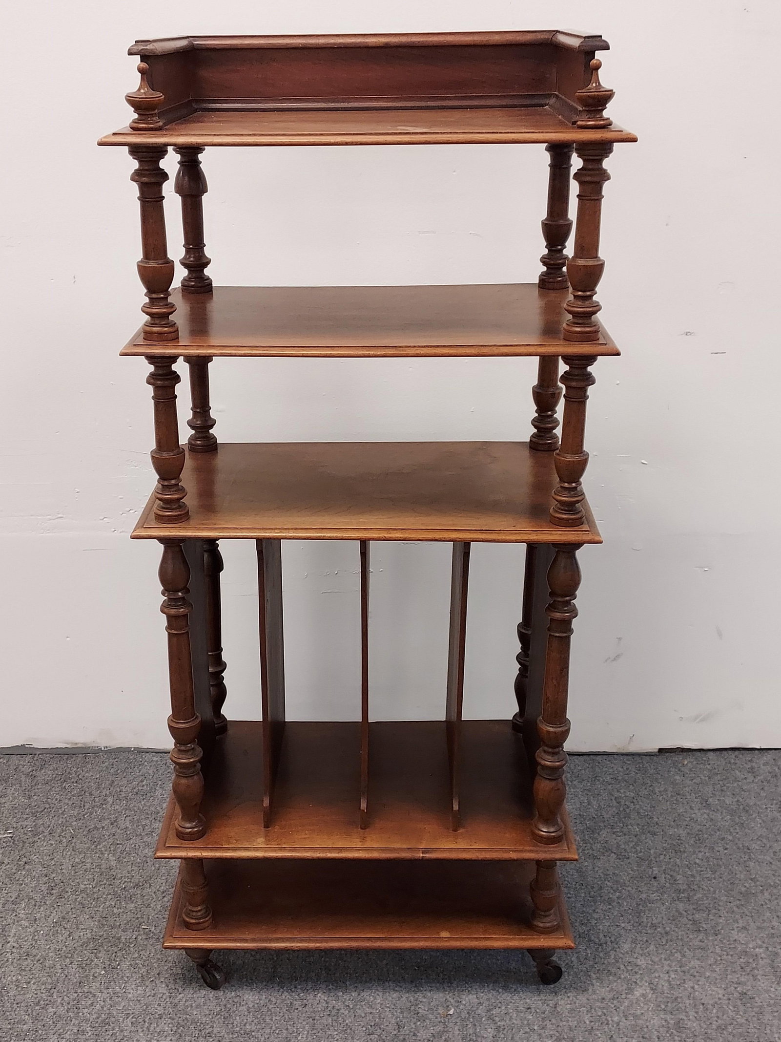 ANTIQUE VICTORIAN MINI PECAN WOOD ETAGERE SHELF: Antique Victorian mini pecan wood etagere shelf unit on castors, with lower magazine rack. Measures a total of 43.5" tall x 19.75" wide and 11.5" deep. Condition: minor fading to finish, some inconsis