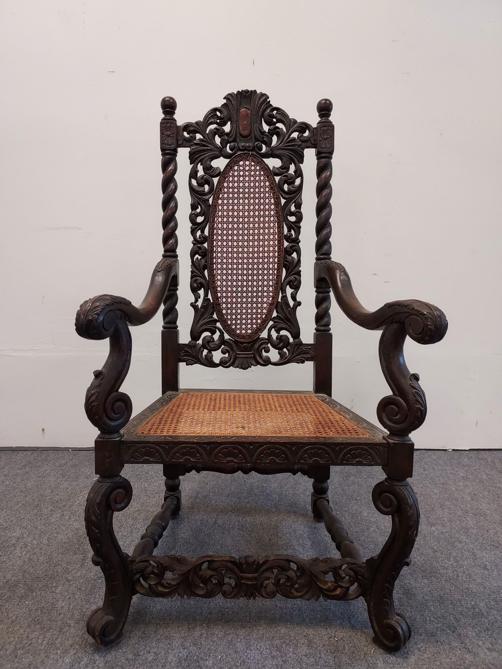 ANTIQUE VICTORIAN CARVED WALNUT ARMCHAIR: Antique Victorian carved walnut armchair with a caned seat and backrest. Measures 49" tall x 26" wide and 28" deep. Condition: a few small damages to caning on the back rest, normal expected signs of