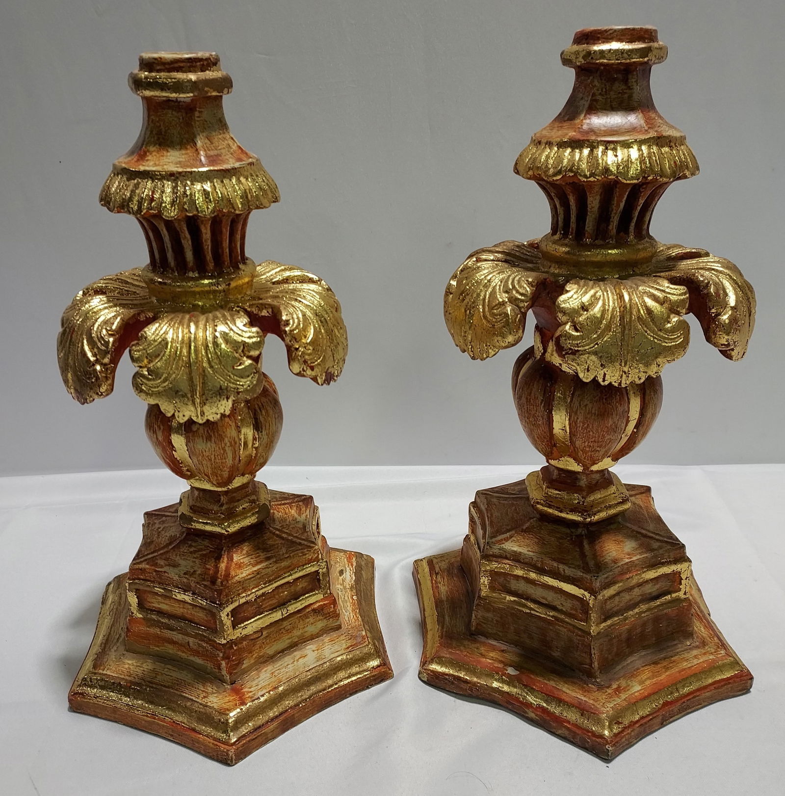H111 A Pair of Wood Italianate Wooden Candlesticks: A pair of wooden Italianate candlesticks with reddish gold gilt distressed finish. 18" x 12" x 12" 2nd quarter 20th C.