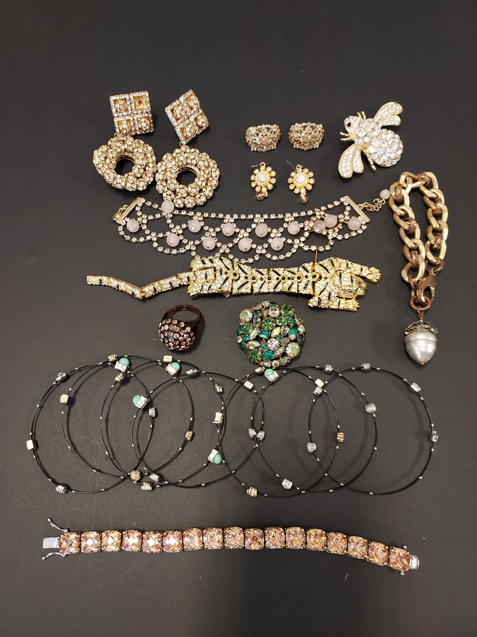 H621 Lot unsigned costume jewelry: 16 pcs unsigned costume jewelry: 1-6- six unsigned black bangles set with crystals and blue colored stones (missing); 7- an unsigned pair of gold tone clip-on earrings with orange rhinestones; 8- an u