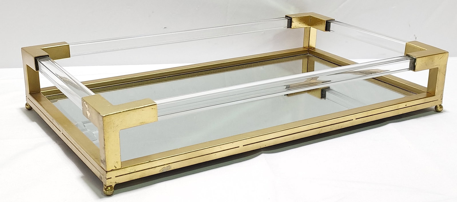 H398 Uttermost Brass & Lucite Tray: Uttermost brass and Lucite tray. Gold leafed metal tray, suspended clear acrylic solid bars on each side, beveled glass and ball feet. 4.5” x 24” x 14.5” 1st quarter 21st C
