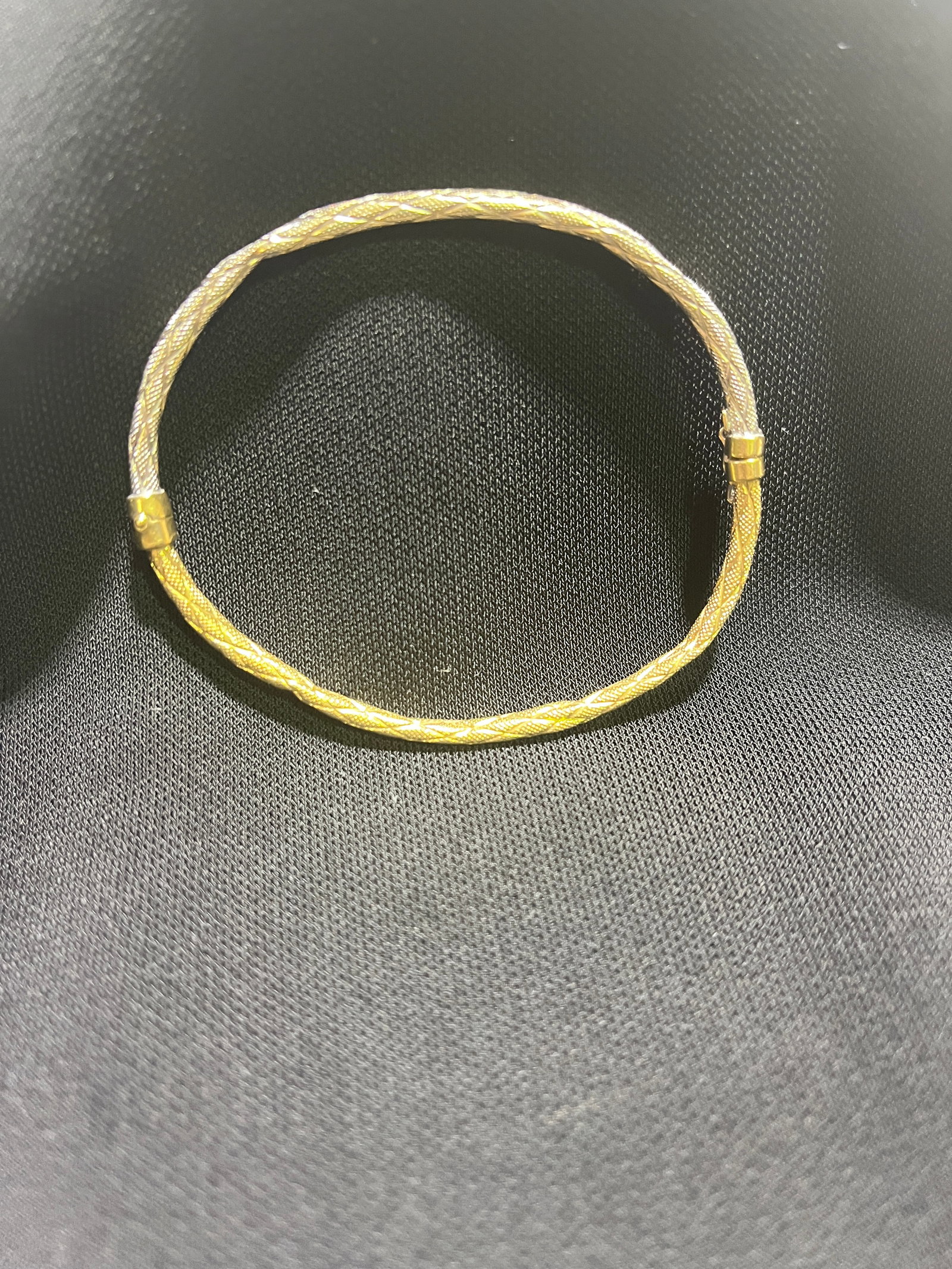 HJ159 18k yellow and white gold bangle: 18k yellow and white gold hinged bangle with safety clasp. Half the bangle is white gold and the other half is yellow gold. Wheat sheaf design. Slightly bent out of shape, and small area is dented. 2.