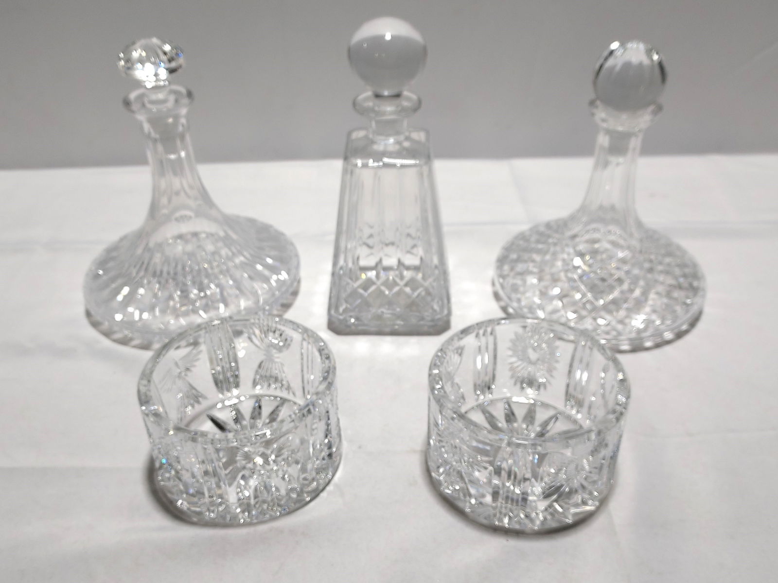 H923 Waterford Decanters and Wine Coasters: 2 Waterford crystal decanters: 1 ship's decanter and 1 liquor decanter. 2 Waterford crystal wine coasters 3" x 5.5". and one Edinburgh International ship's decanter (some mineral stains and questionab