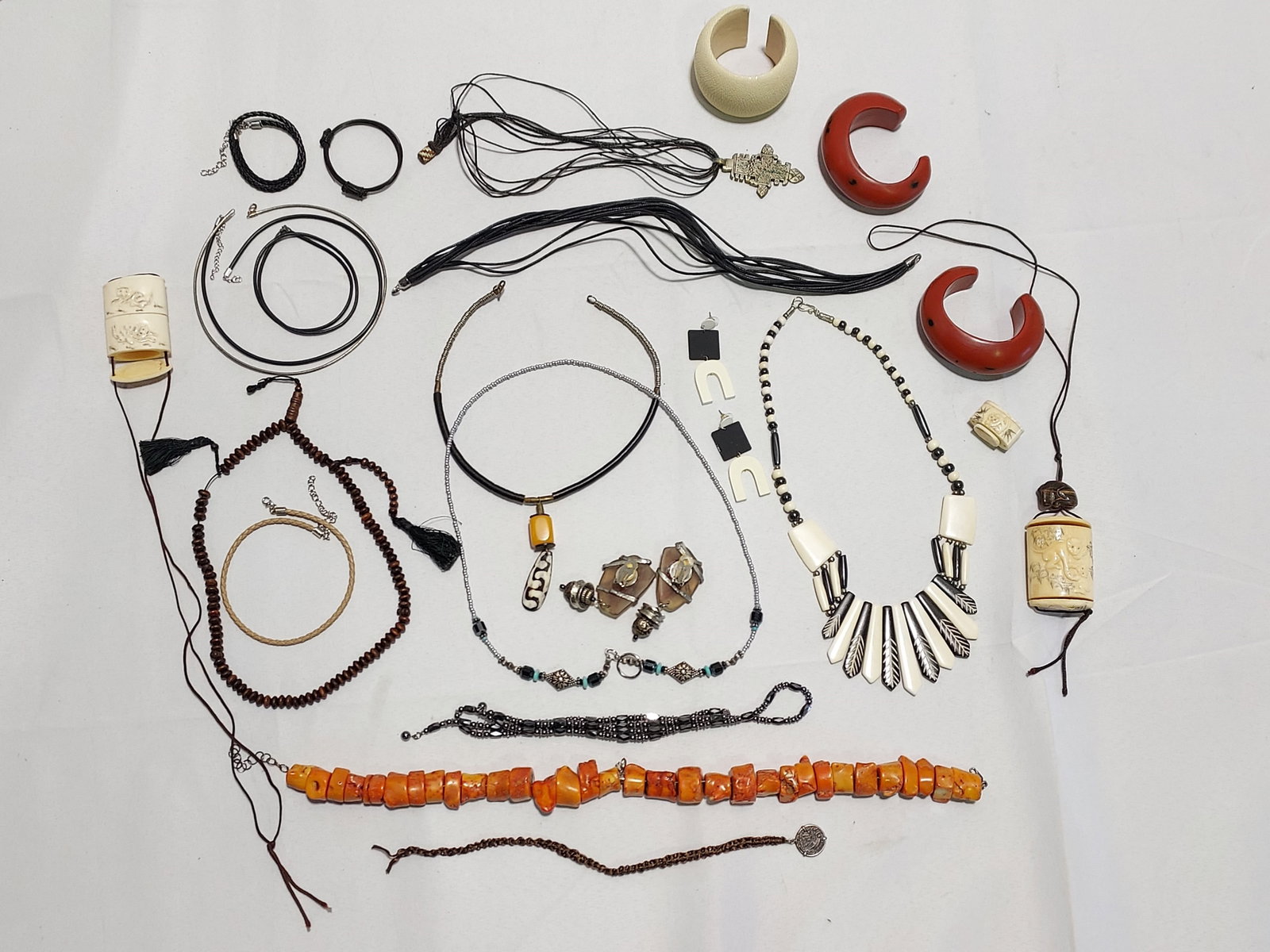 H650 22 pcs sgned and unsigned costume jewelry: 22 pcs sgned and unsigned costume jewelry: 1- signed Senti beige stingray leather cuff, 2- an unsigned carved bone box string necklace with feline motif, 3- an unsigned orange chunky coral necklace, 4