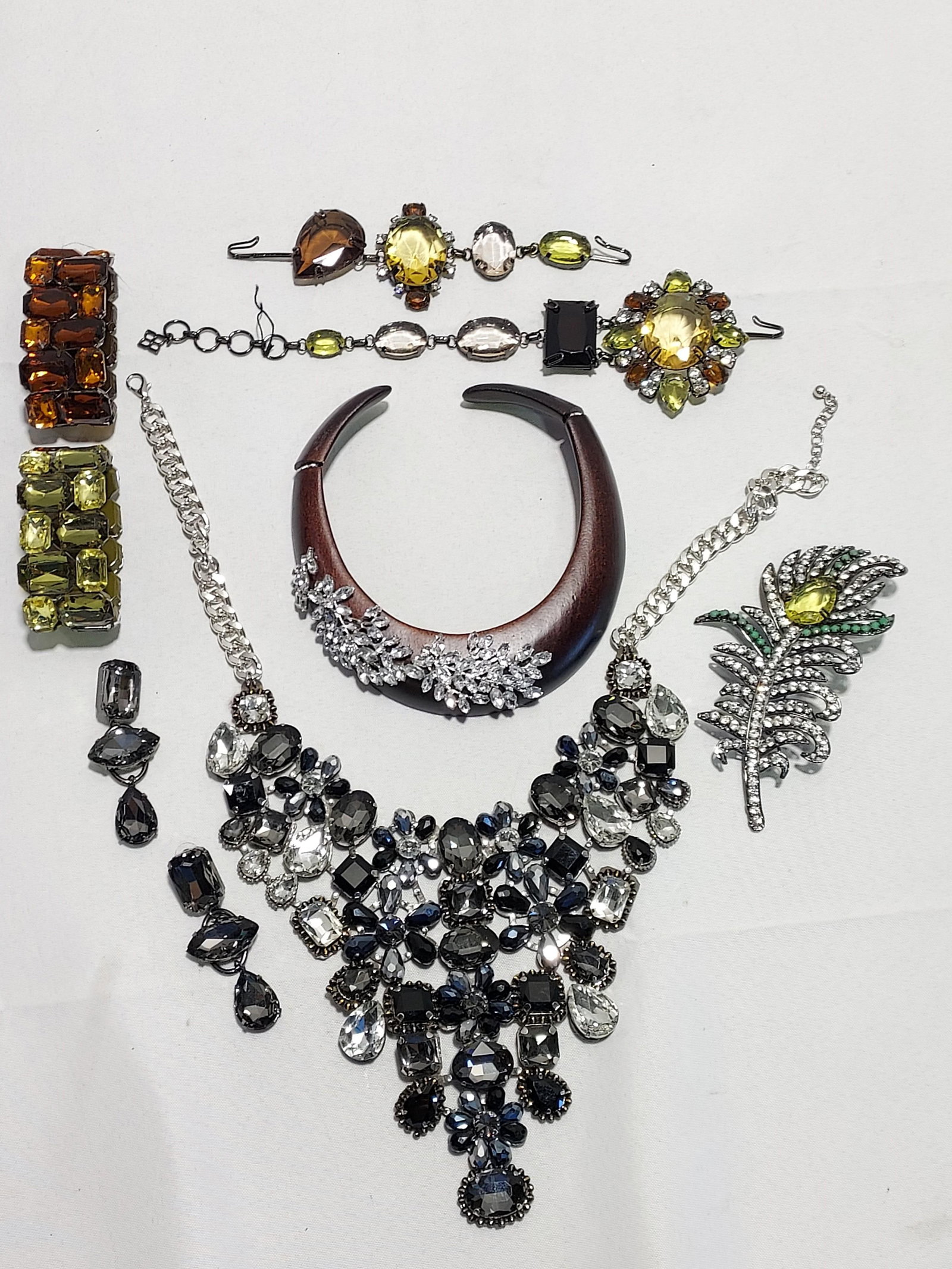 H604 6 pc signed and unsigned costume jewelry: 6 pc signed and unsigned costume jewelry: 1- BCBG rhinestone and large brown, green and yellow crystal necklace with large rhinestone feather motif; 2 a wood composite hinged collar choker with rhines