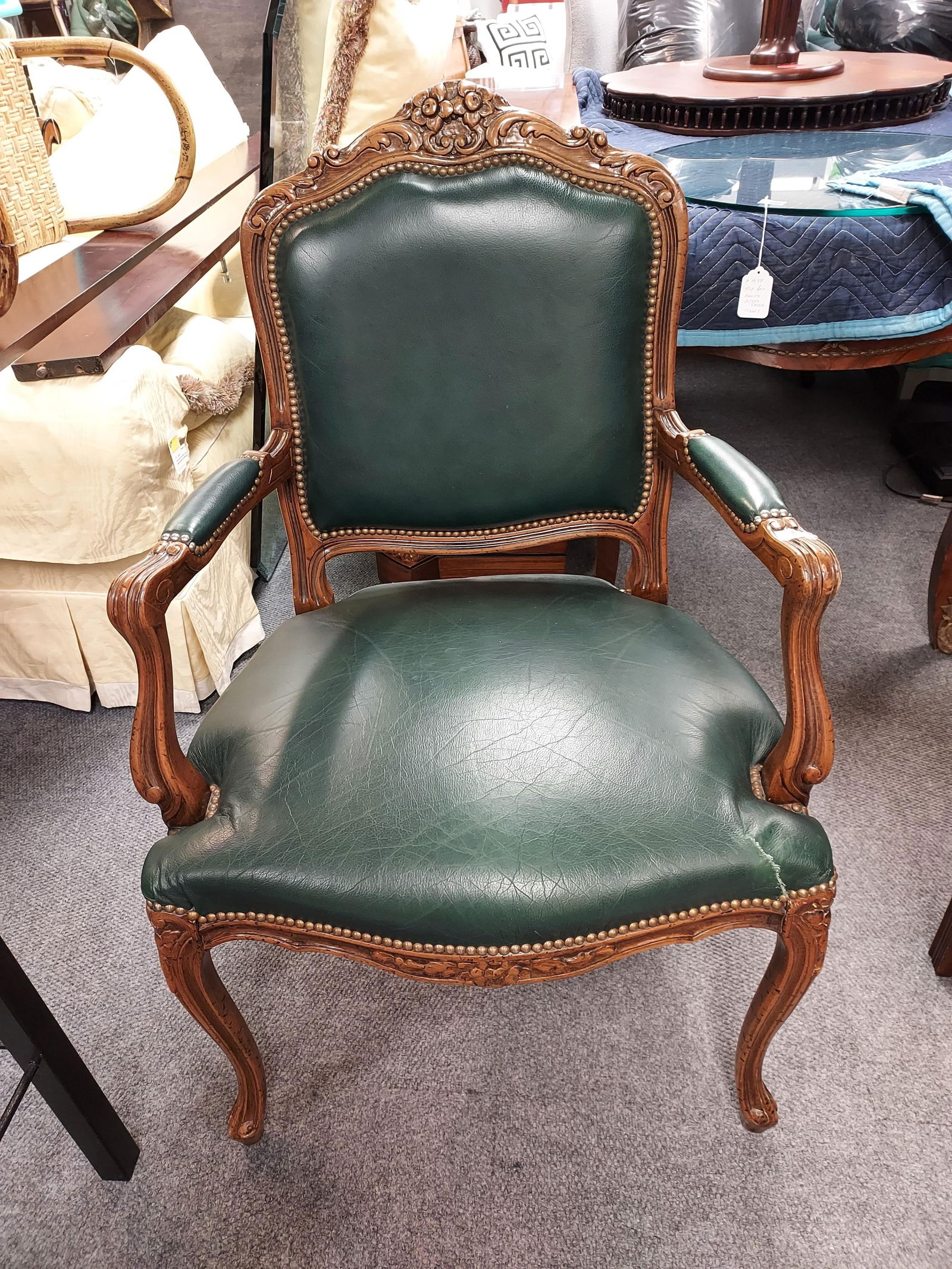 H1094 French Bergere style Chair:: French bergere style Chair: Wood frame; exposed arms, green leather and upholstery nails. 5" repaired tear to front right side of seat. 40.5" x 25" x 23.5". 3rd quarter 20th C