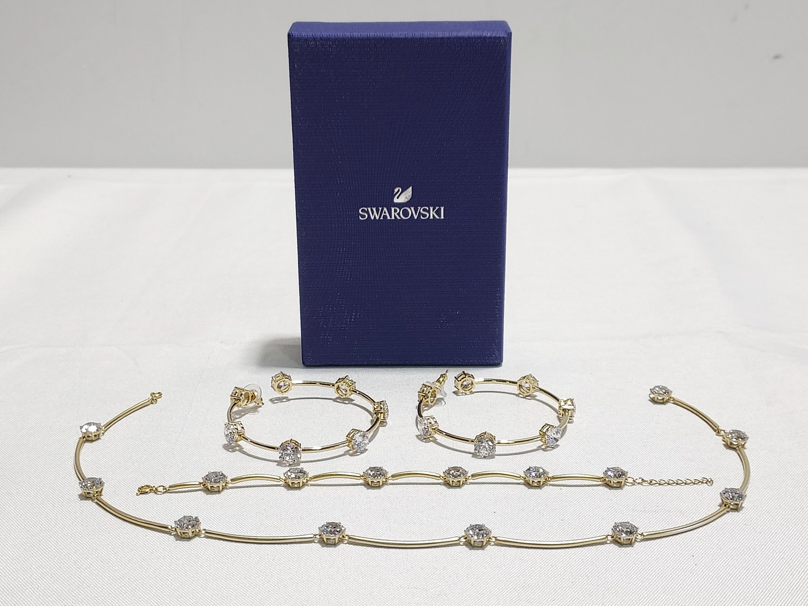 H579 Swarovski Constella parure: Swarovski Constella parure consisting of necklace, hoop earrings and bracelet. Gold tone metal set with Swarovski solitaire cut crystals. 4th quarter 20th C. Dimensions: Necklace 17", Hoops (inner dim