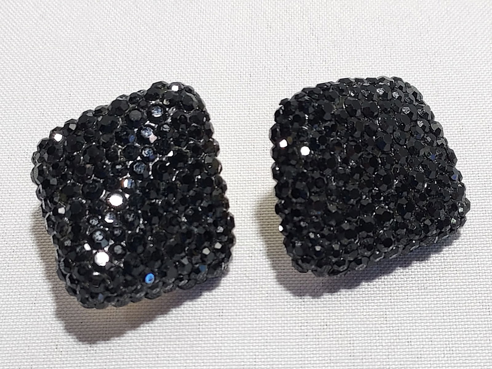 H545 A pair of jet black earrings: Clip on, gold tone metal. Tops are completely covered with shimmery jet black crystals. 4th quarter 20th C. Dimensions approx. 1.5"x1.8"