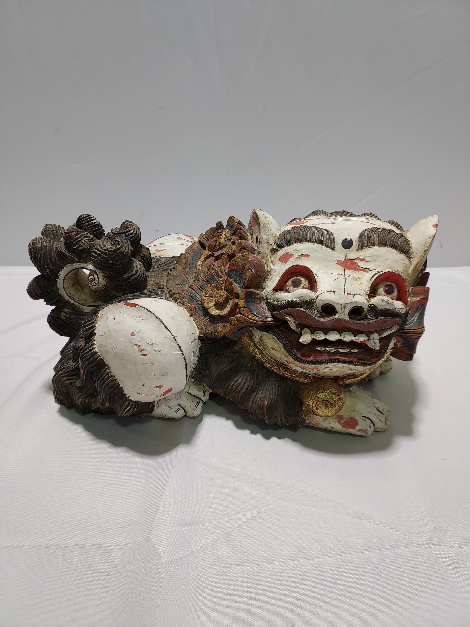 H1238 Temple Lion: wood carved, painted, distresse: Solid wood Temple Lion; hand carved, polychrome painted. Inpainting especially of face and paws, chipped paint, dings. 9" x 17.5" x 7.5"